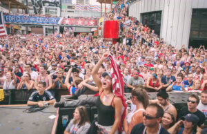 Fans cheering on Team USA in FIFA World Cup at watch party.