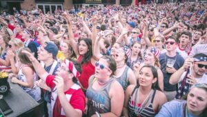 A crowd of fans cheering on America at a FIFA World Cup watch party.